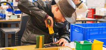 afbeelding: man met boormachine achter tafel