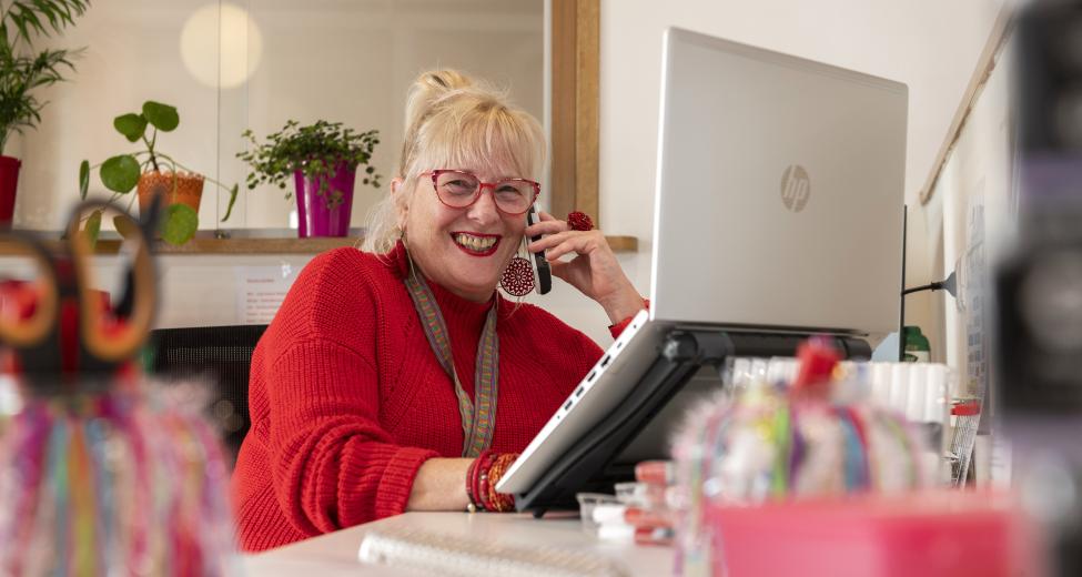 Afbeelding: vrouw achter laptop aan de telefoon