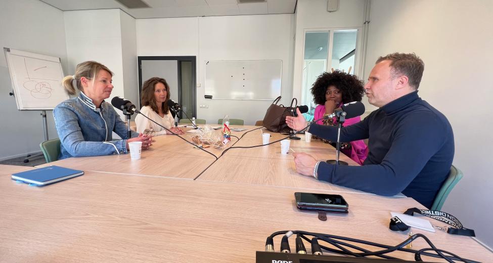 afbeelding 4 mensen aan een tafel met microfoons