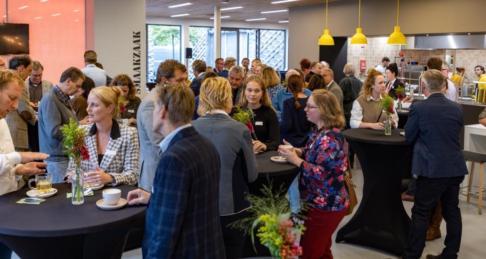 afbeelding: groep mensen aan statafeltjes