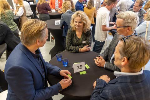 Afbeelding: pratende mensen aan statafel 