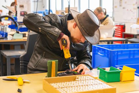 afbeelding: man met boormachine achter tafel