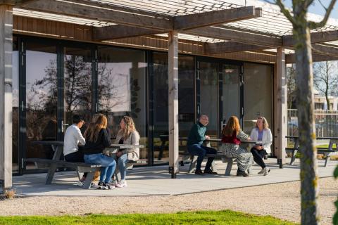 Afbeelding mensen pratend buiten aan zitbanken