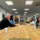 afbeelding mensen aan een lange tafel met microfoons