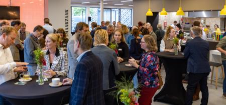 afbeelding: groep mensen aan statafeltjes