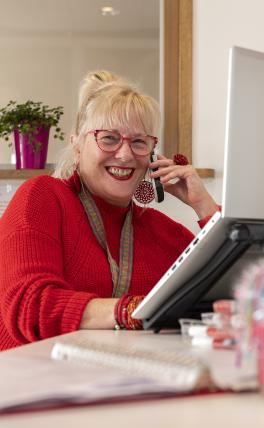 Afbeelding: vrouw achter laptop aan de telefoon